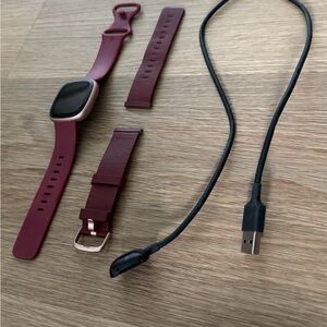 Fitbit Versa 4 smartwatch in plum with additional leather strap